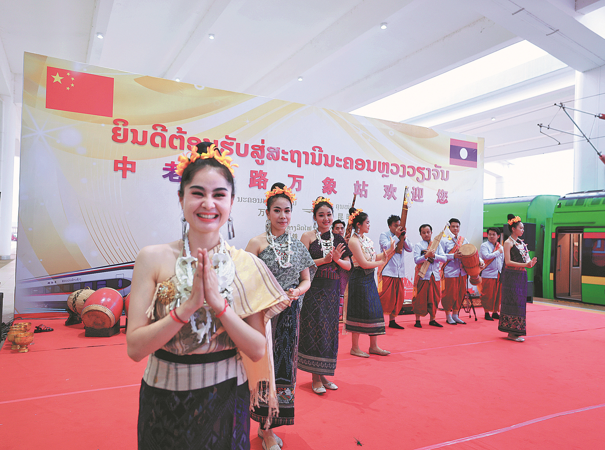 Kakitangan warga Laos di Vientiane menyambut penumpang yang menaiki tren rentas sempadan pertama dari Kunming, ibu kota provinsi Yunnan. (Xinhua/Xing Guangli)