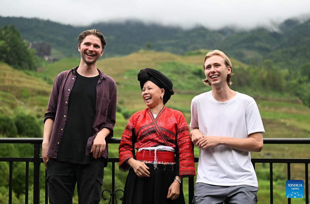 Pan Fenglan (tengah) berbual-bual dengan pelancong dari Jerman di inap desa miliknya di Kampung Dazhai, Kaunti Longsheng, Wilayah Autonomi Guangxi Zhuang, selatan China, pada 26 Jun 2024.