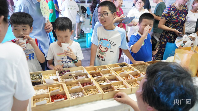 Kanak-kanak belajar cara mengenal pasti herba di pasar malam TCM di Chongqing. (Foto/CNR)