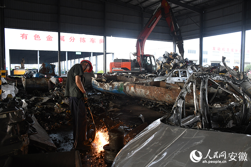 Seorang pekerja merungkai kereta skrap. (People’s Daily Online/Zhou Kun)