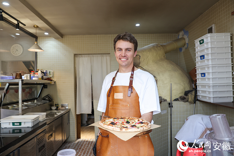 Adrien Brill mempamerkan piza dengan ikan mandarin berbau busuk, makanan istimewa tempatan di Huangshan, Provinsi Anhui di timur China. (Harian Rakyat Dalam Talian/Zhang Jun)