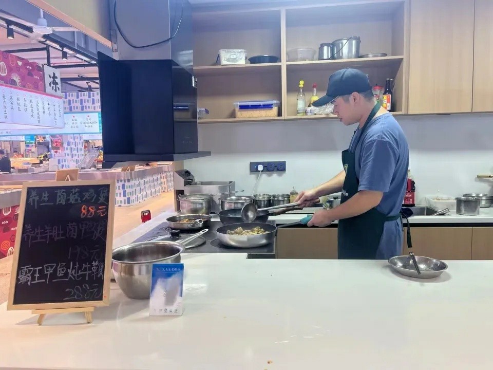 Seorang tukang masak menyediakan hidangan di sebuah gerai di pasar basah. Bahan-bahan yang digunakannya diperolehi terus oleh pelanggan dari pasar yang sama. (Gambar ihsan individu yang ditemuduga)