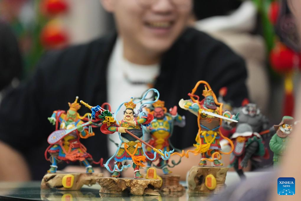 Kang Jian, pewaris teknik pembuatan doh patung kecil mempamerkan hasil seninya di dalam kereta api. (Xinhua/Wang Song)