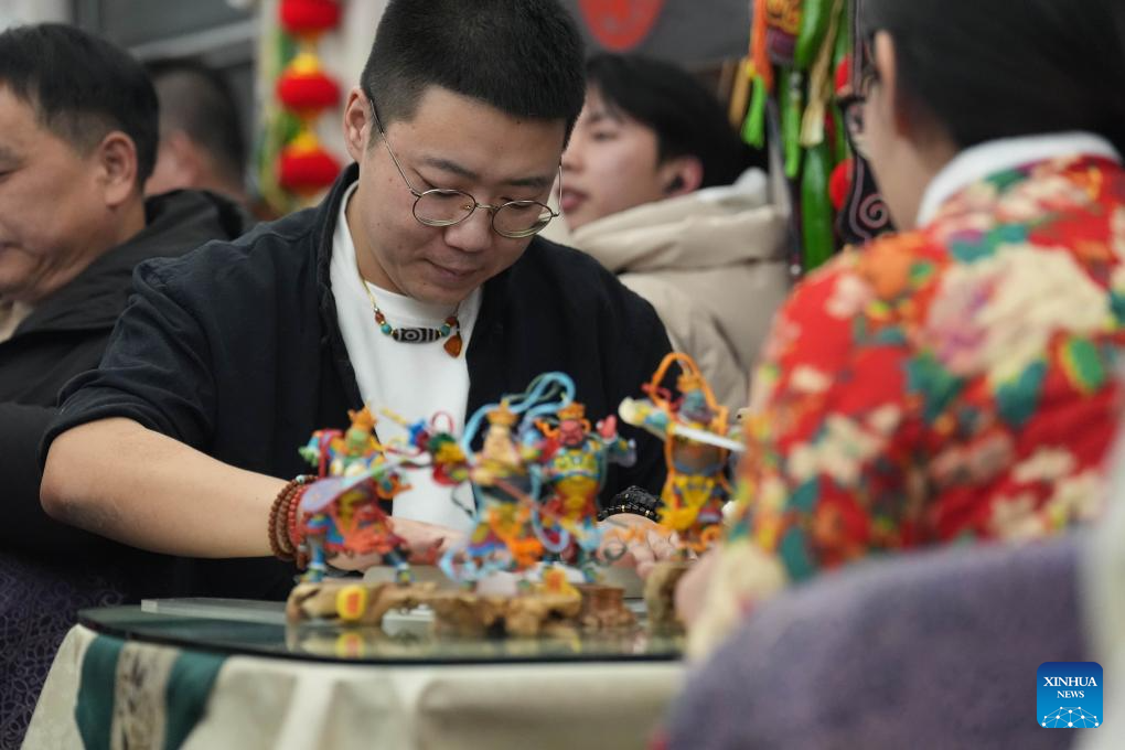 Kang Jian, pewaris teknik pembuatan doh patung kecil mempamerkan kebolehan seninya di dalam kereta api. (Xinhua/Wang Song)