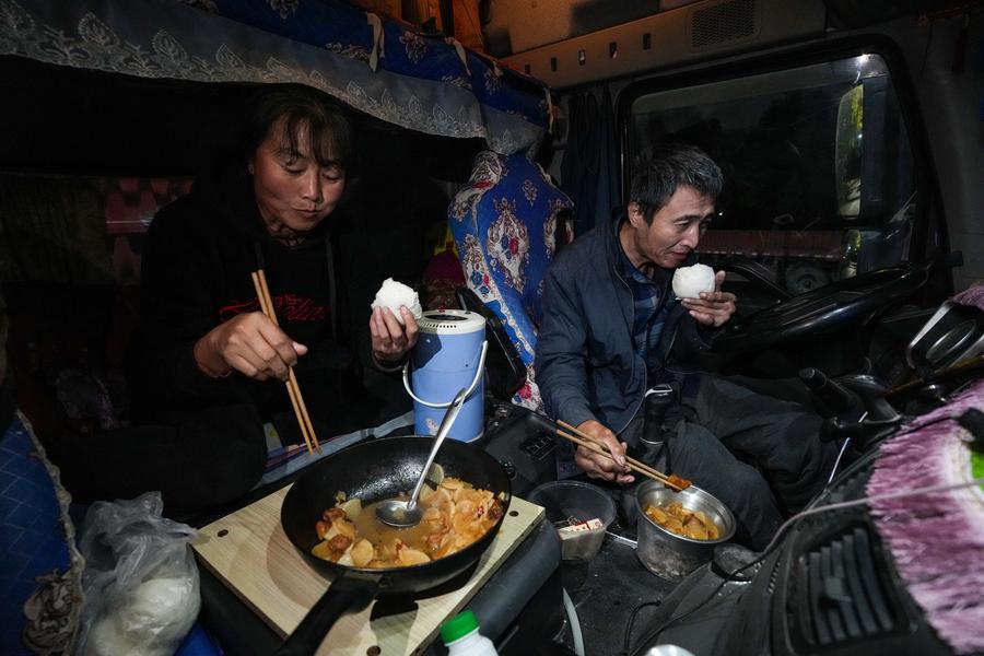 Kong Lingjian (kanan) dan isterinya Wang Yanqing sedang makan malam di dalam trak pada 16 Januari 2025 (Xinhua/Chen Yehua).