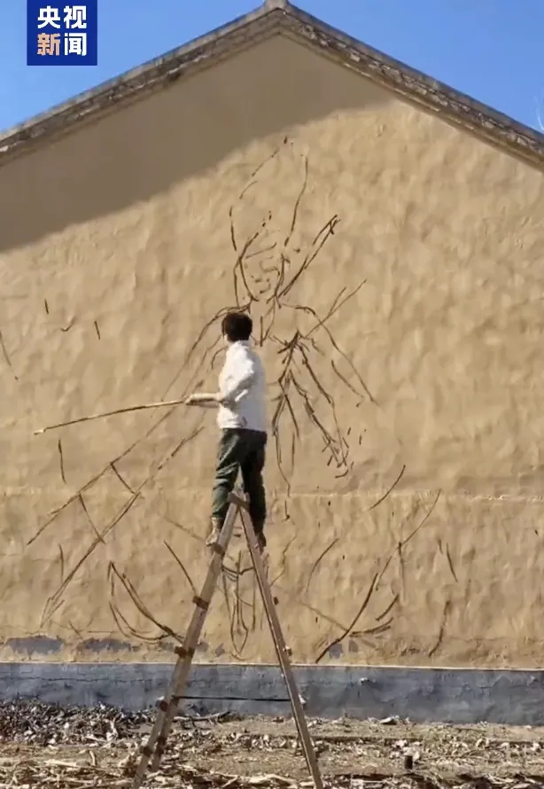 Shen Jingyu sedang menghasilkan mural gergasi yang menampilkan blokbuster animasi China, ‘Ne Zha 2’ di sebuah dinding di kampung Shenjiacun. (Foto oleh CCTV News)