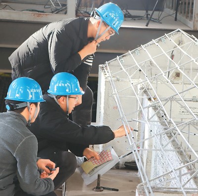 Penyelidik sedang menandakan rekahan pada model rumah cetakan 3D di tapak eksperimen. (Foto oleh Kang Pu)