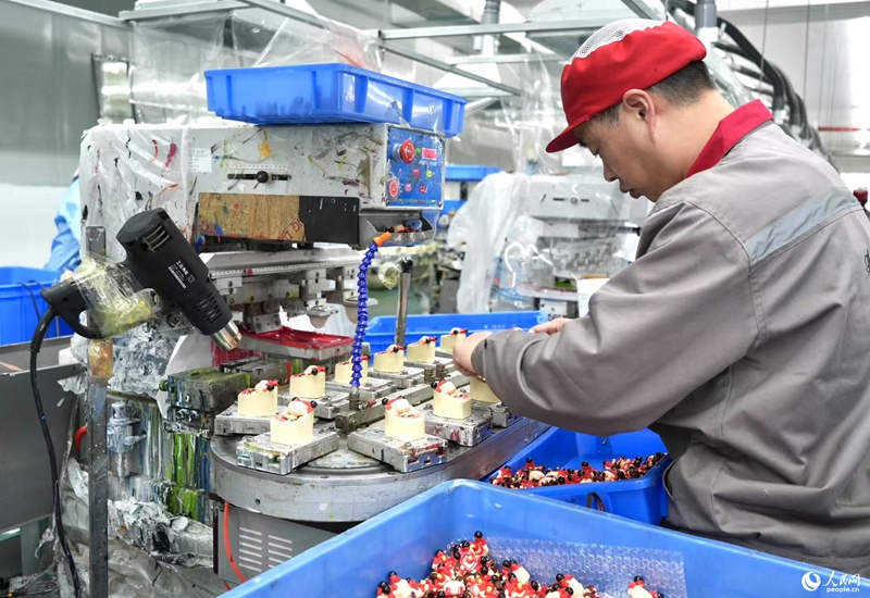 Seorang pekerja sedang bekerja di barisan pengeluaran patung figura Ne Zha. (People’s Daily Online/Liu Shan)