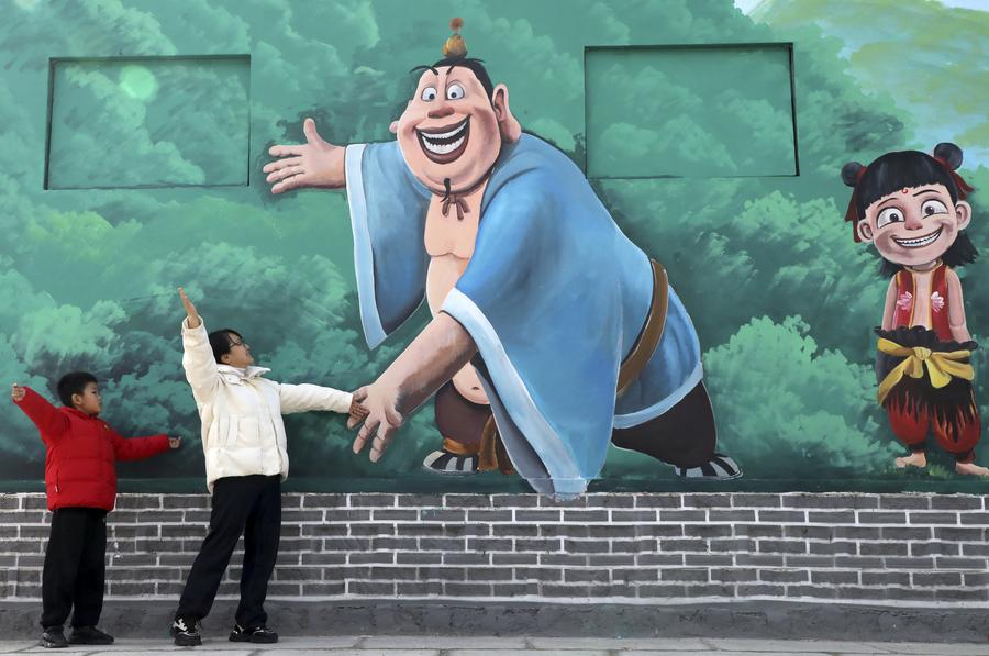 Pelancong bergambar dengan lukisan dinding yang menampilkan filem animasi blokbuster, ‘Ne Zha 2’ di Kampung Dongfeng, Kaunti Boxing, di Binzhou, Provinsi Shandong pada 1 Mac 2025. (Xinhua/Chen Bin)