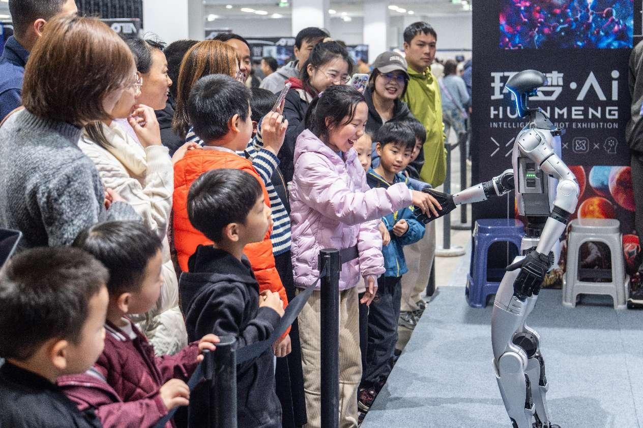 Di sebuah pameran robot AI di Suzhou, Provinsi Jiangsu pada 28 Februari 2025, seorang kanak-kanak di berjabat tangan dengan robot yang dibangunkan pleh Unitree Robotics, pendahulu dalam pembangunan robot manusia. (People’s Daily Online/Wu Xue)