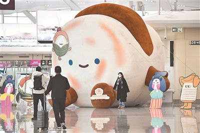 Seorang penumpang bergambar dengan latar belakang ukiran gergasi snek tempatan ‘Roujiamo’, atau burger China di balai berlepas di Terminal 5 Lapangan Terbang Antarabangsa Xianyang Xi’an, Provinsi Shaanxi, barat laut China. (Xinhua/Shao Rui)