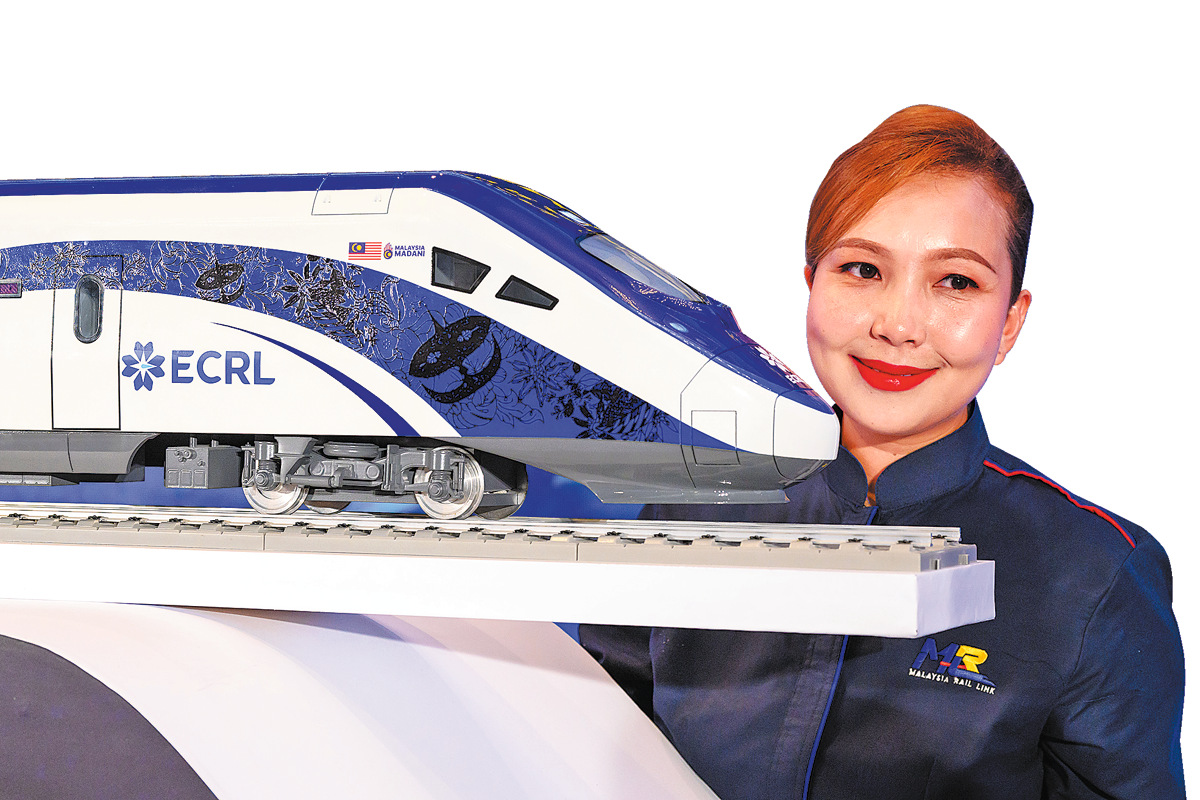 Seorang petugas mempamerkan sebuah model kereta api elektrik pelbagai unit semasa upacara pemeteraian perjanjian bersama antara CCCC dan Malaysia Rail Link di Putrajaya, pada 18 Disember 2024. (Xinhua/Chong Voon Chung)