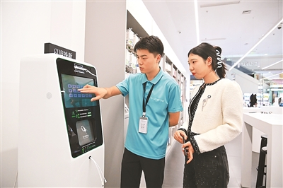 Seorang kakitangan (kiri) menunjukkan kepada pengguna cara menggunakan robot kitar semula di pusat beli-belah di daerah Shapingba, Perbandaran Chongqing di barat daya China. (Foto/Sun Kaifang)