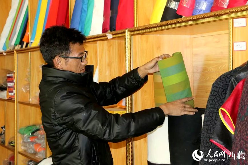 Lhachung, eksekutif di pangkalan pekerjaan dan keusahawanan di kaunti Zhanang, bandar Shannan, Wilayah Autonomi Xizang barat daya China, mengatur pakaian di sebuah kedai di pangkalan itu. (Foto/Tsering Norbu)