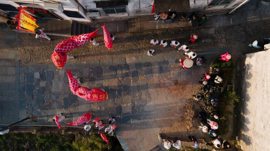 Foto sudut udara bertarikh 24 Mac 2025 ini memaparkan pengunjung sedang menikmati pertunjukkan tanglung berbentuk ikan di pekan purba Yuliang di Kaunti Shexian, Bandar Huangshan, Provinsi Anhui di timur China. (Xinhua/Zhang Duan)