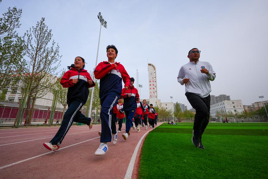 Jurulatih Rozaji Amatjan (pertama dari kiri) dan pemain bola sepak perempuan bawah 13 tahun pasukan Bandar Artux mengambil bahagian sesi latihan di Bandar Artux, Kawasan Autonomi Kirgiz Kizilsu di Wilayah Autonomi Uygur Xinjiang pada 14 April 2025. (Xinhua/Xu Hongyan)