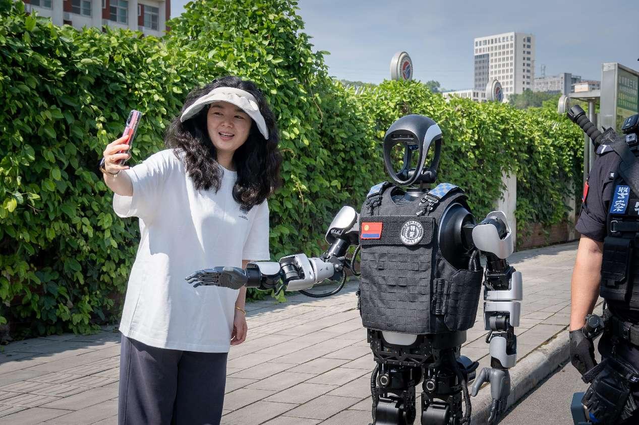 Seorang wanita bergambar dengan robot humanoid dalam misi rondaan di Mianyang, wilayah Sichuan barat daya China, 27 April 2025. (People's Daily Online/Tang Chao)