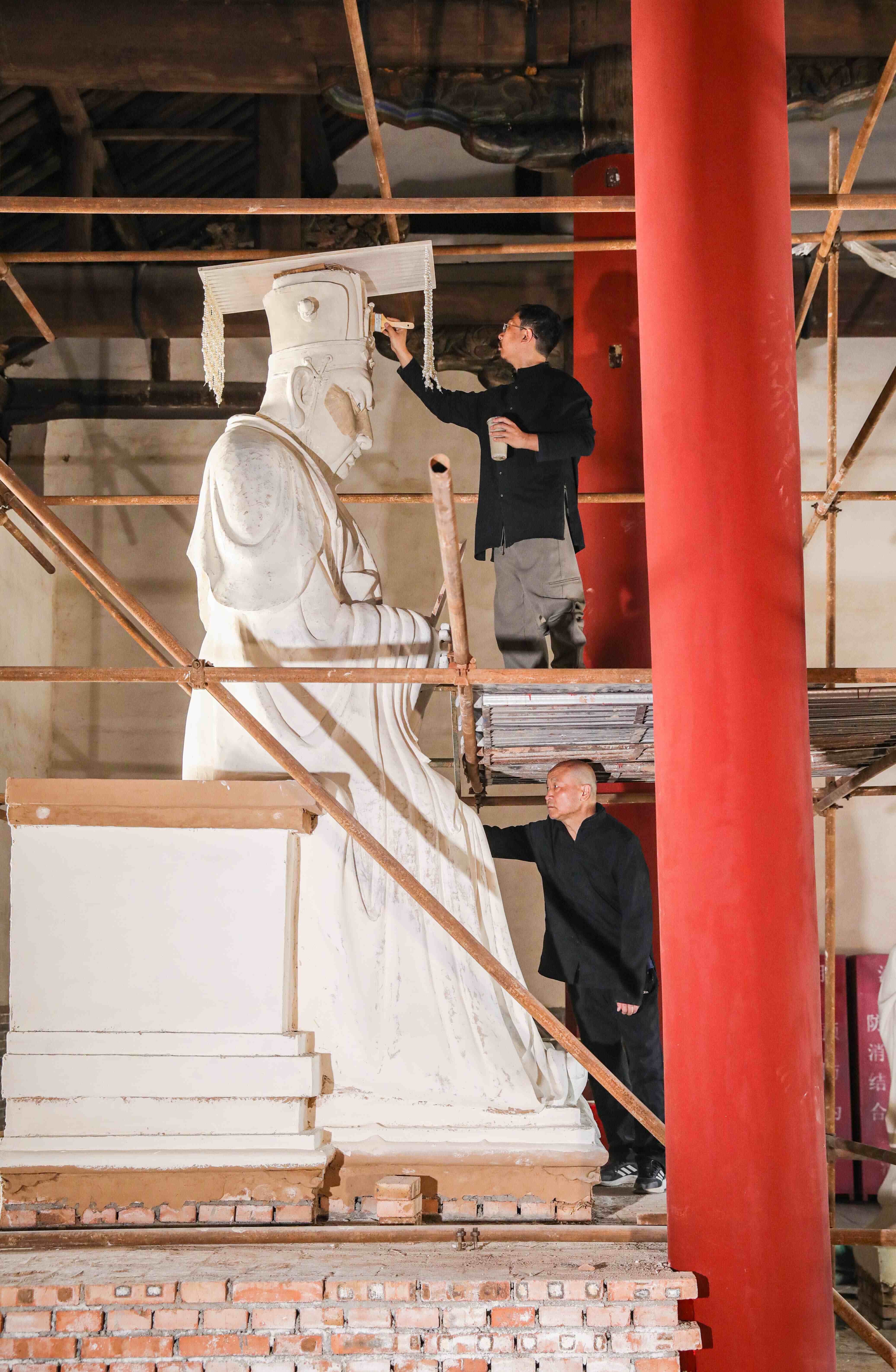 Liu Ziqun, artisan China yang lahir pada 1990an, dan bapanya yang merupakan seorang artis ukiran berwarna, bersama-sama menyiapkan ukiran berwarna di Kuil Guandi di bandar Linfen, Provinsi Shanxi di utara China. (Foto oleh Wang Fan)