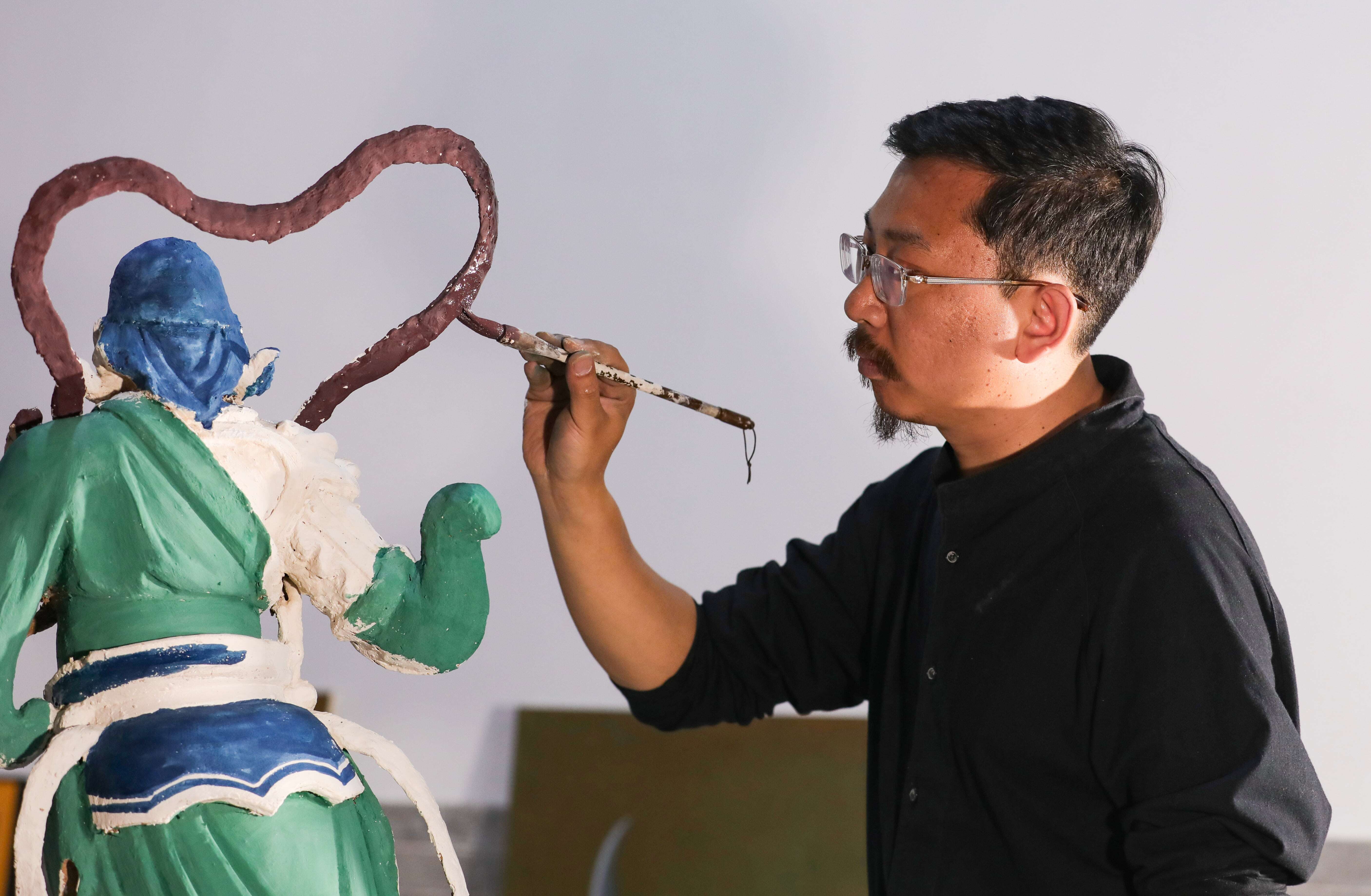 Liu Ziqun, seorang artisan China yang dilahirkan pada tahun 1990-an, mewarnakan ukiran. (Foto oleh Wang Fan)