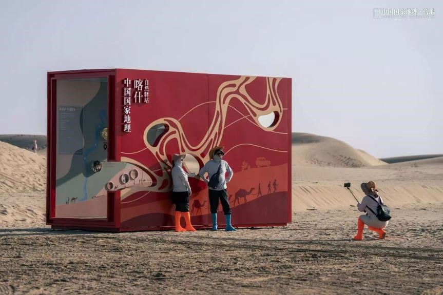 Pelancong sedang membuat gaya untuk bergambar di hadapan bilik pameran bertemakan padang pasir di sebuah tapak pelancongan di Makit. (Foto ihsan Chinese National Geography)