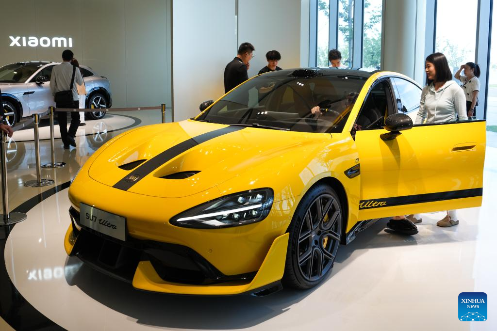 Pengunjung mempelajari mengenai kenderaan tenaga baharu di kilang automobil Xiaomi di Beijing, pada 16 Jun 2025. (Xinhua/Zheng Huansong)