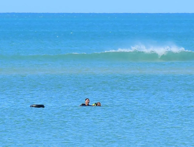 Zhang Junqiao (kiri) menyelamatkan seorang wanita yang lemas di pantai di Dar es Salaam, Tanzania.
