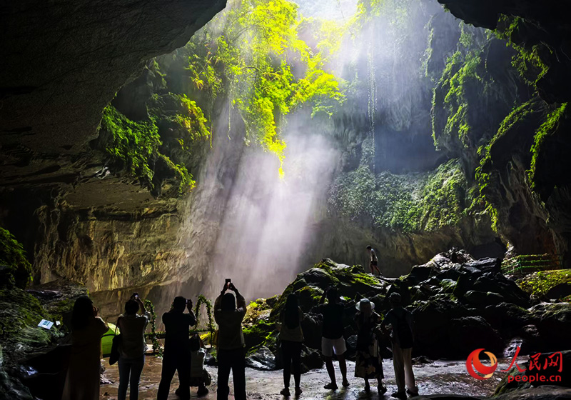 Pelancong mengambil gambar cahaya matahari dengan kesan Tyndall di gua kars di tempat peranginan pelancong Gunung Jinzhong, yang terletak di kaunti Yongfu, bandar Guilin, Wilayah Autonomi Zhuang Guangxi di selatan China. (People’s Daily Online/Lei Qijun)