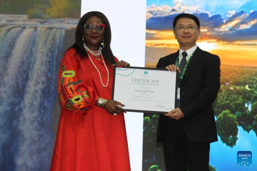 Musonda Mumba (kiri), setiausaha agung Konvensyen untuk Tanah Lembap, menyerahkan sijil akreditasi bandar tanah lembap antarabangsa kepada seorang wakil dari Hangzhou, Provinsi Zhejiang, pada 24 Julai 2025 di Victoria Falls, Zimbabwe. Sejumlah sembilan bandar raya China telah ditauliahkan sebagai bandar tanah lembap antarabangsa pada Khamis semasa pembukaan Mesyuarat Ke-15 Persidangan Pihak Penjanji kepada Konvensyen Ramsar mengenai Tanah Lembap (COP15) yang diadakan di bandar peranginan Victoria Falls, Zimbabwe, menjadikan jumlah keseluruhan bandar seumpama itu di China kepada 22 bandar, iaitu yang terbanyak di dunia. (Xinhua/Tafara Mugwara)