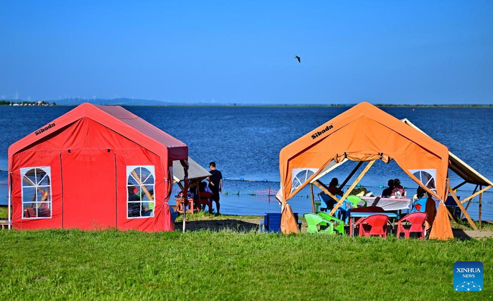 Orang ramai berteduh di dalam khemah di tepi Sungai Songhua di Harbin, Provinsi Heilongjiang, timur laut China pada 6 Julai 2025. (Xinhua/Yang Wei)