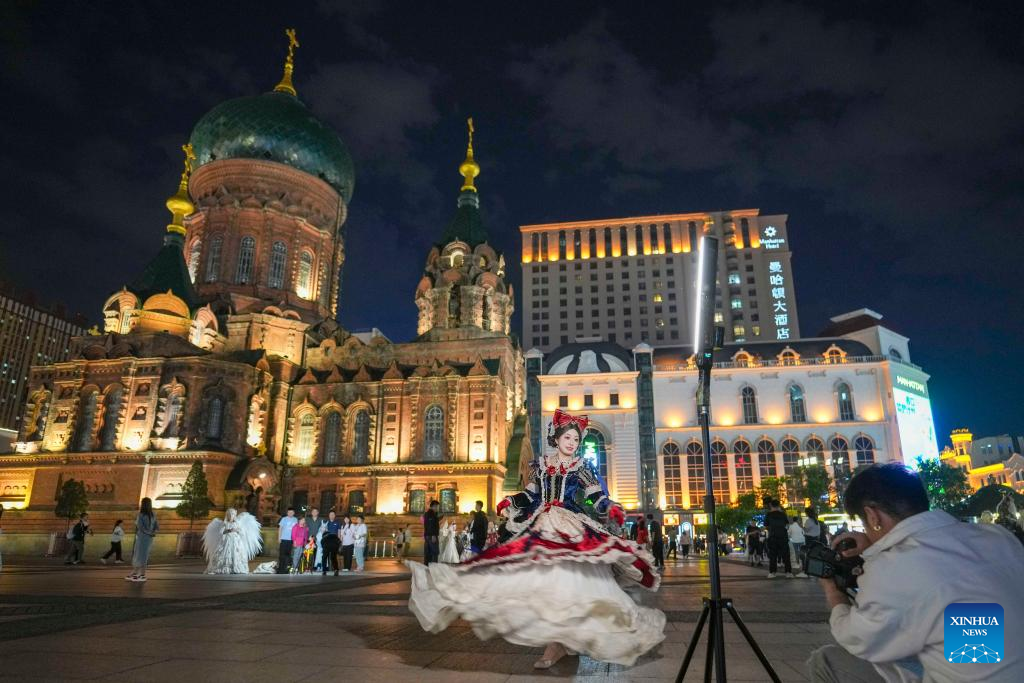 15.	Pelancong yang penuh bergaya mengambil gambar dengan berlatarbelakangkan Gereja Besar St. Sophia di Harbin, Provinsi Heilongjiang, timur laut China pada 8 Jun 2025. (Xinhua/Wang Jianwei)