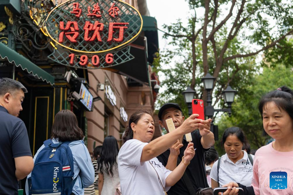 16.	Para pelancong mengamil swafoto dengan ais krim Modern di Central Street di Harbin, Provinsi Heilongjiang, timur laut China pada 1 Ogos 2025. (Xinhua/Xie Jiangfei)