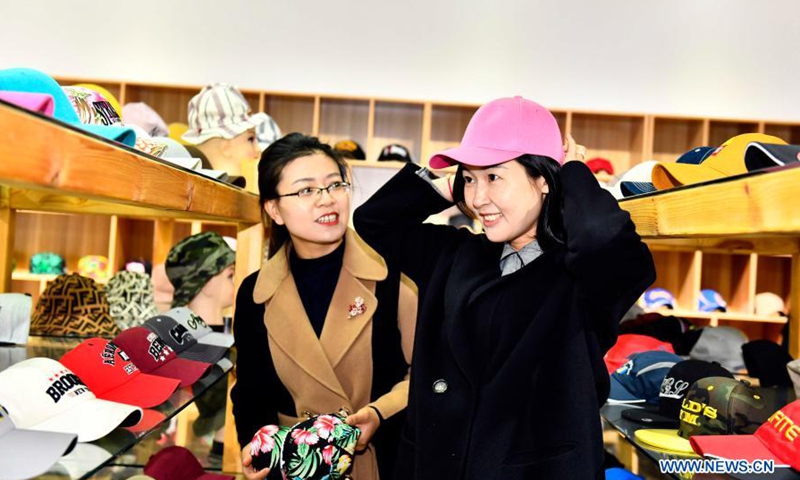 Pengunjung cuba memakai topi di bilik pameran di pekan Ligezhuang di Jiaozhou, Provinsi Shandong, timur China, 4 Mac 2021. (Foto oleh Xinhua)