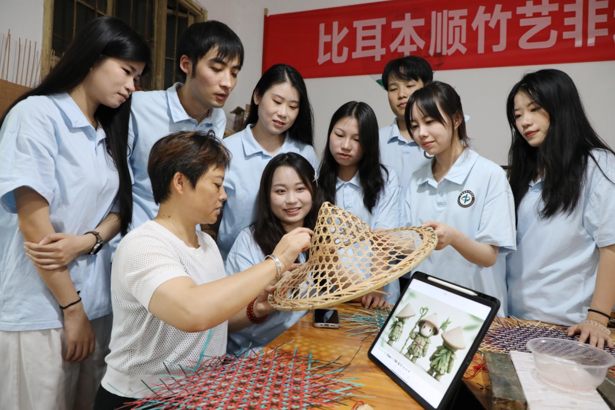 Mahasiswa dari Universiti Perhutanan dan Teknologi Selatan Tengah memberi panduan kepada seorang pewaris tenunan buluh tentang penggunaan AI dalam rekaan di kaunti Baojing, Kawasan Autonomi Tujia dan Miao Xiangxi, Provinsi Hunan di tengah China. (Foto oleh Yu Caihua)