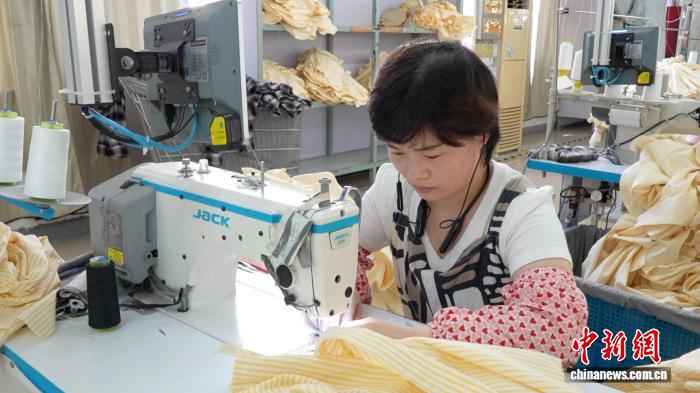 Seorang wanita bekerja di sebuah kilang pakaian kanak-kanak di pekan Zhili, daerah Wuxing, bandar Huzhou di Provinsi Zhejiang, timur China.