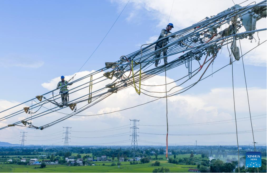Foto dari sudut udara yang diambil pada 16 September 2025 ini memperlihatkan pekerja sedang melaksanakan kerja-kerja cantuman konduktor untuk projek penghantaran tenaga terus UHV ±800 kV Gansu-Zhejiang di kaunti Nanling, Wuhu, Provinsi Anhui. (Xinhua/Liu Junxi)