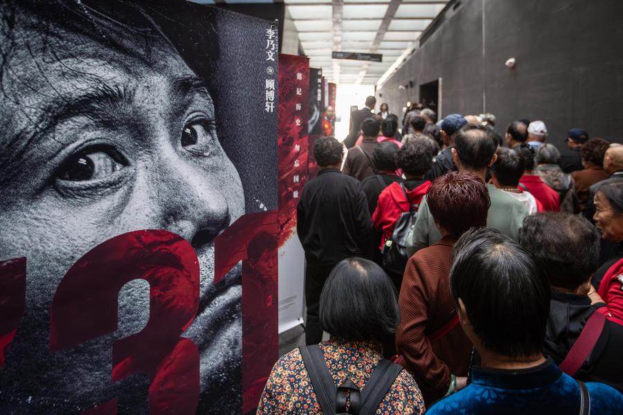 Orang ramai berjalan melintasi poster filem ‘Evil Unbound’ di Dewan Pameran Bukti Jenayah oleh Unit 731 Askar Imperial Jepun di Harbin, Provinsi Heilongjiang, timur laut China pada 18 September 2025. (Xinhua/Zhang Dawei)