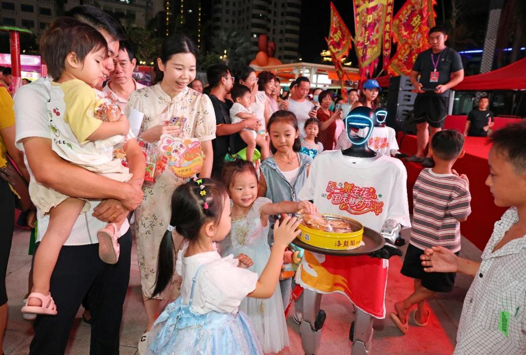 Robot perkhidmatan sedang mengagihkan kuih bulan kepada pejalan kaki di hadapan sebuah pusat beli-belah di Sanya, Provinsi Hainan pada 6 Oktober 2025. (Foto oleh Li Xueshi)